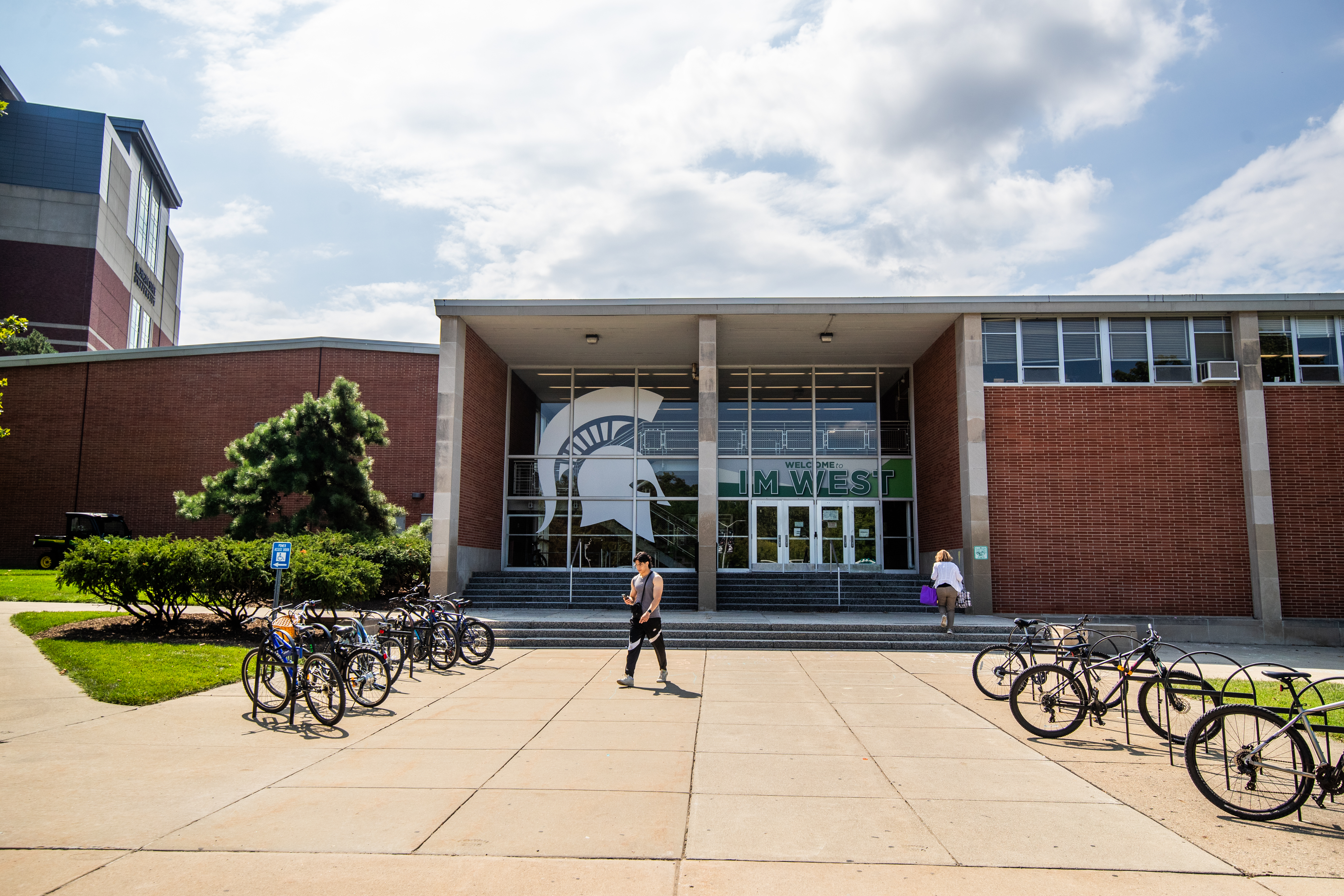 Photo of IM West building. Students are seen walking to and from the building.