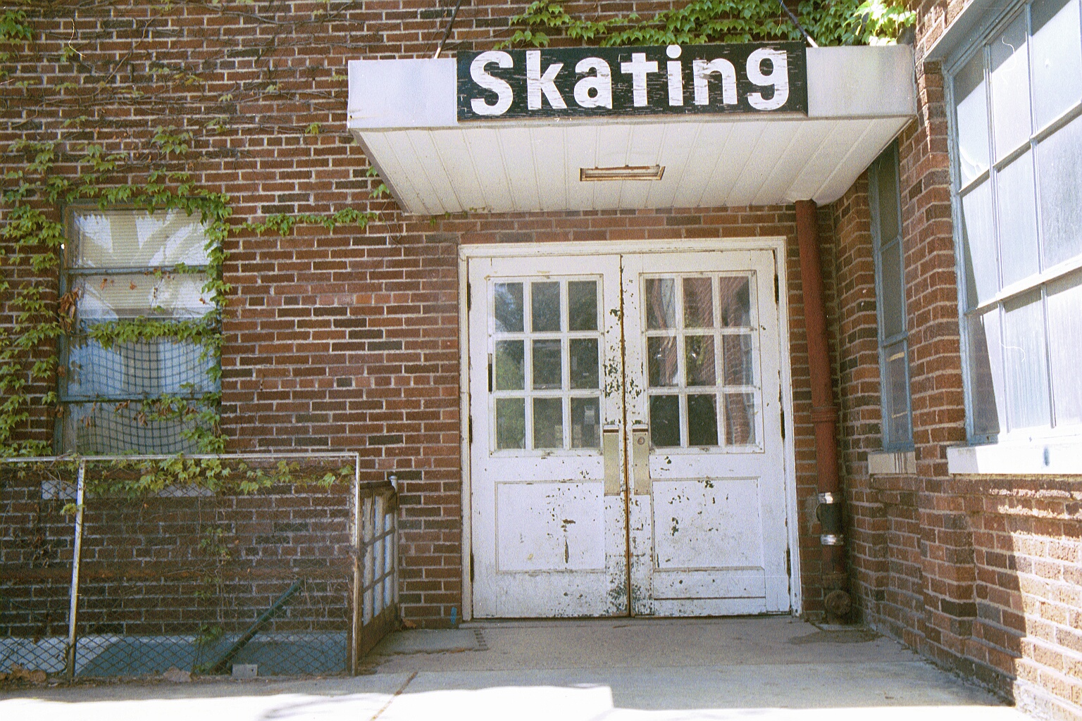 Side door of Dem Hall. A large black sign is hung above labeled "Skating"